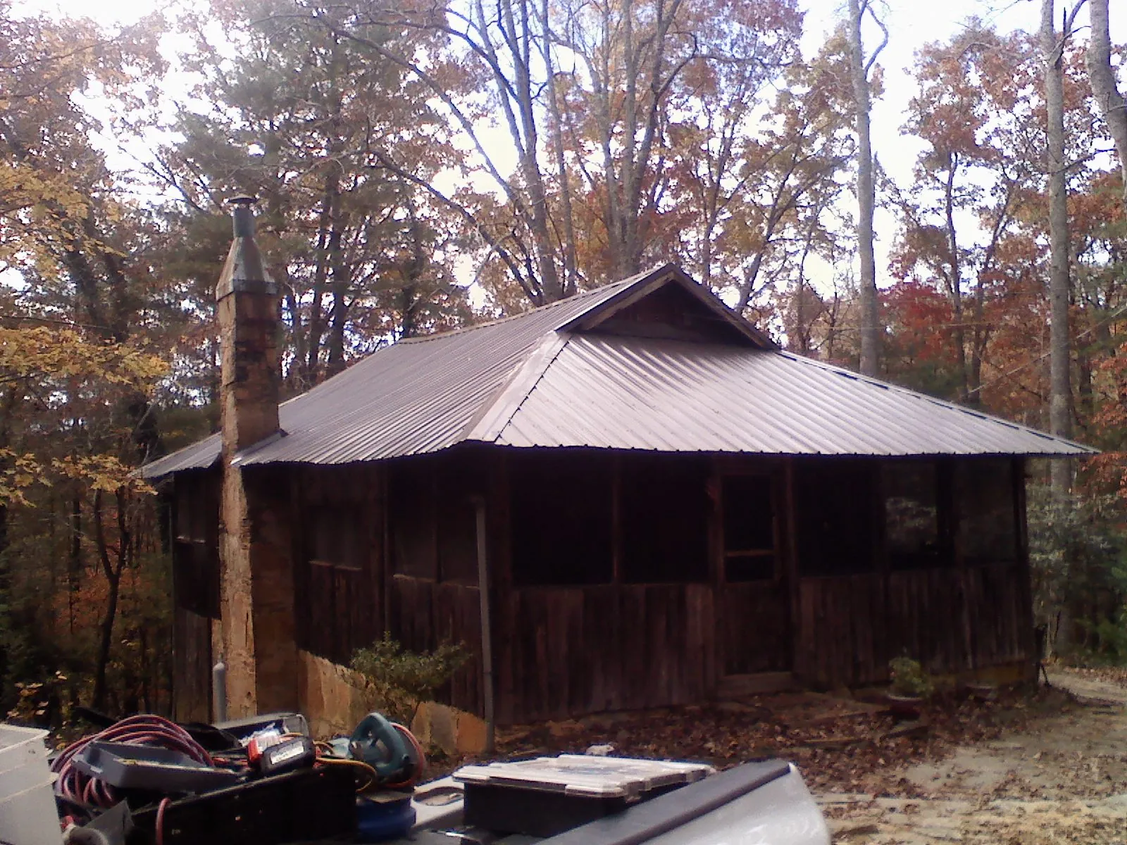 Brown metal hip roof on an old cabin with a stone chimney in Lexington